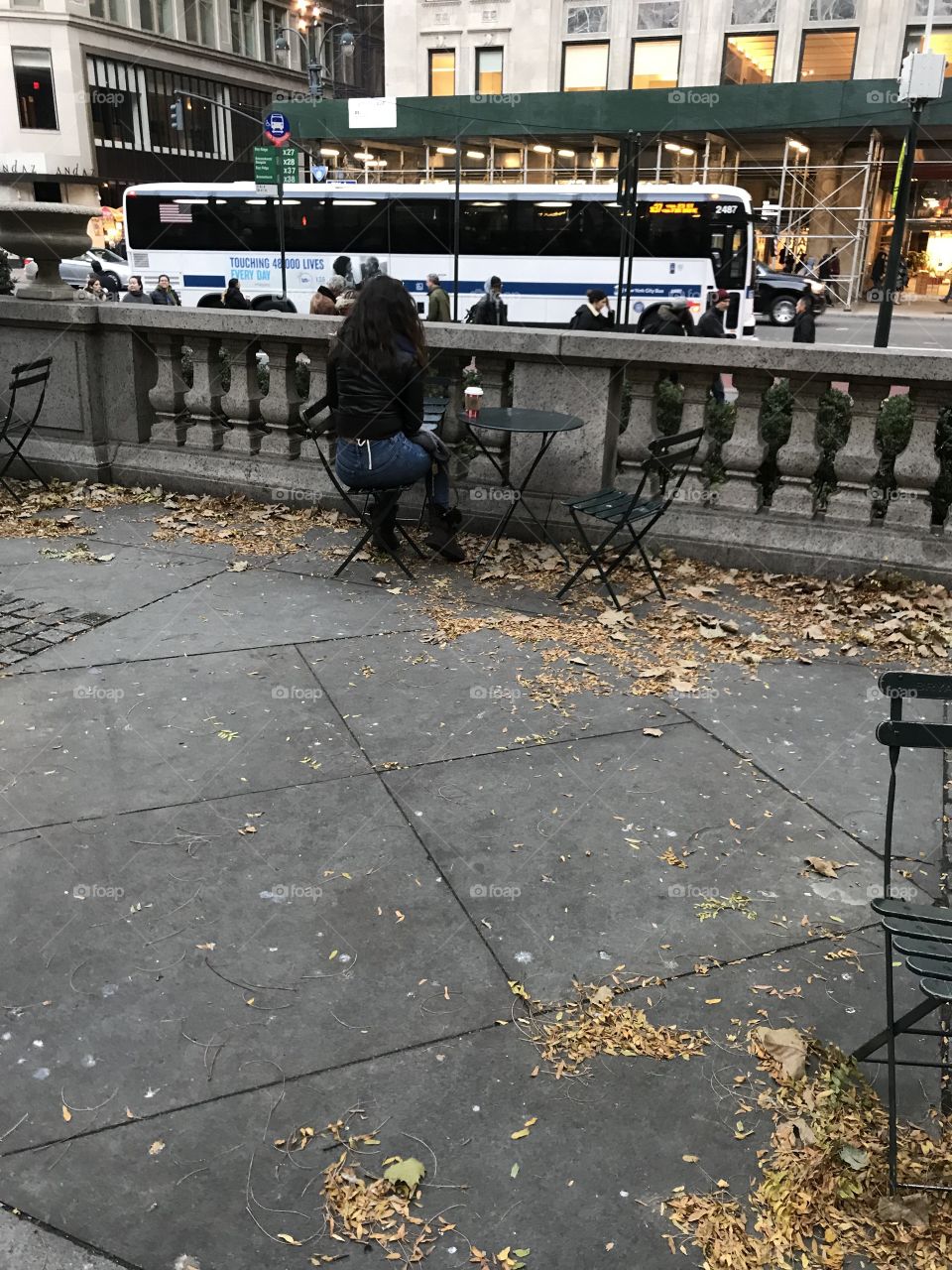Beautiful girl seated in front of the main branch of the New York Public Library from the rear.