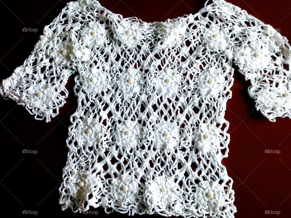 A beautiful handcrafted work made with great care.  A white crochet blouse, with several flowers.