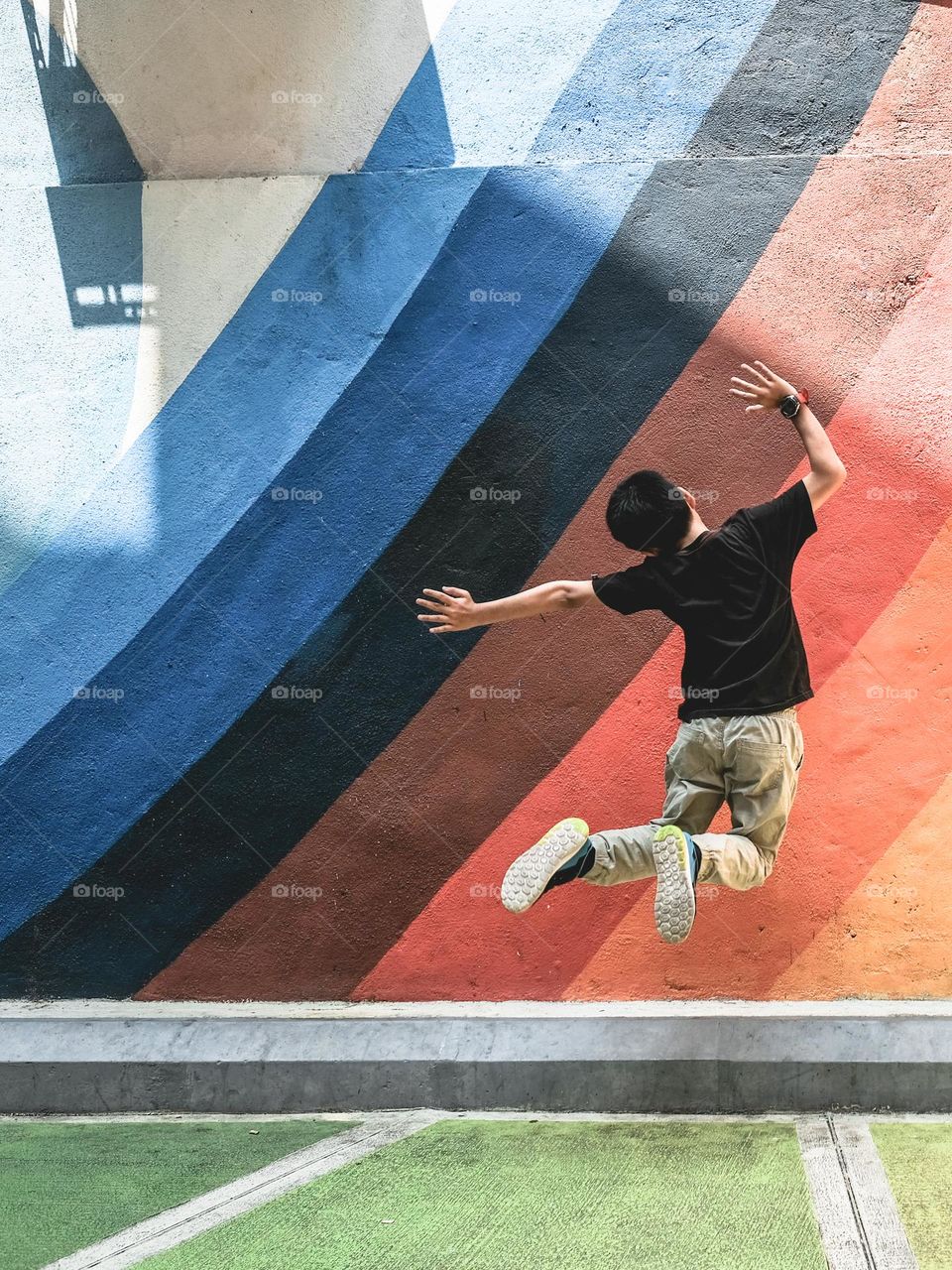 My son doing a jumping joy infront of a new colorful painted mural in KuaLa Lumpur Malaysia