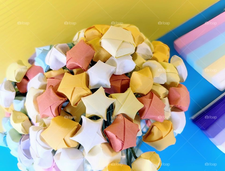 Colourful origami paper stars on yellow and blue background.
