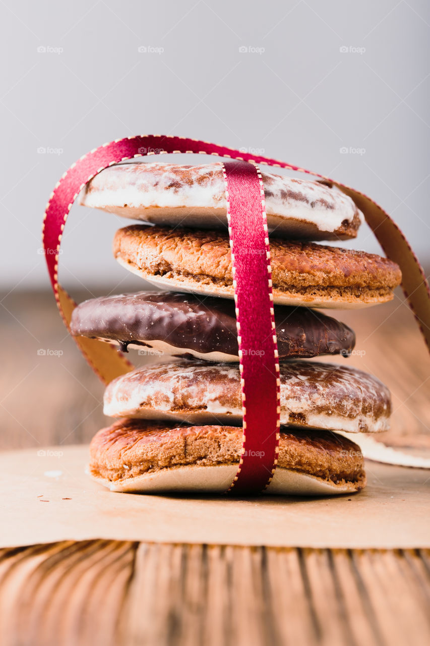 A few gingerbread cookies wrapped in ribbon on wooden table. Plain background. Portrait orientation