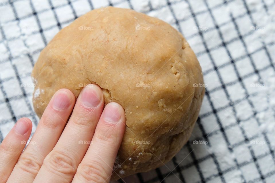 Close up of hand kneading ready dough for American peanut butter cookies  on the checkered napkin