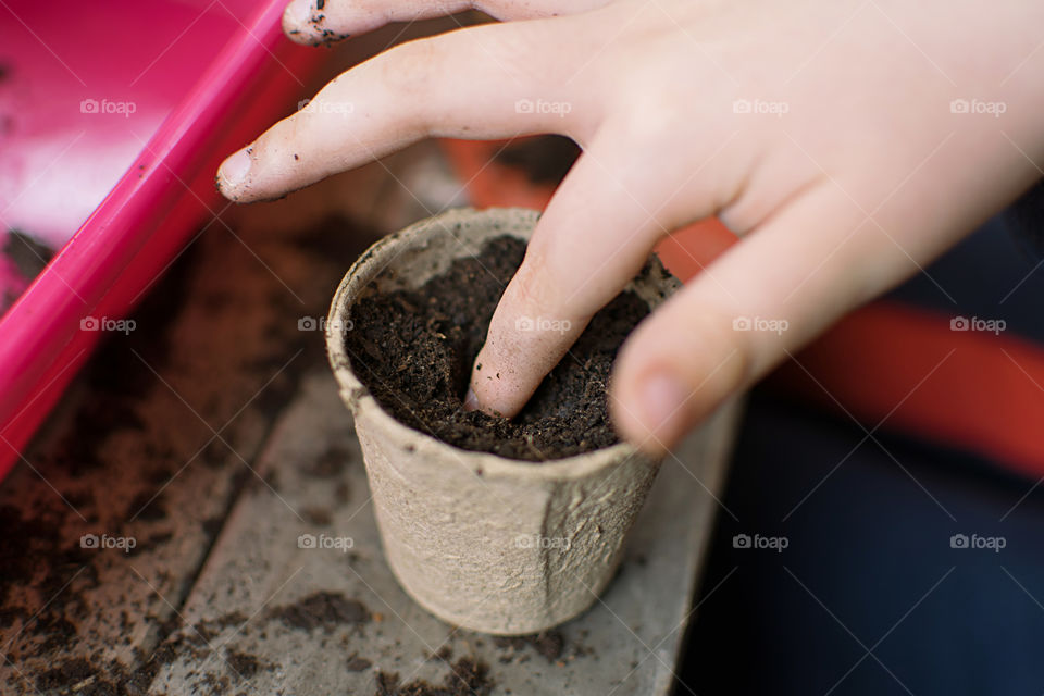 Children learning to plant seeds in garden at home