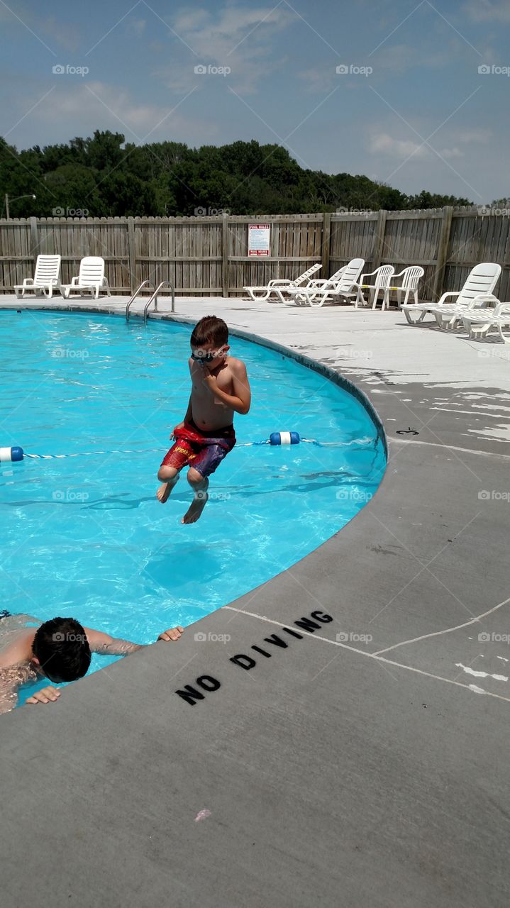 Summer at the pool. Spending time at the pool on a hot day. My son jumps over the "No diving" sign. 