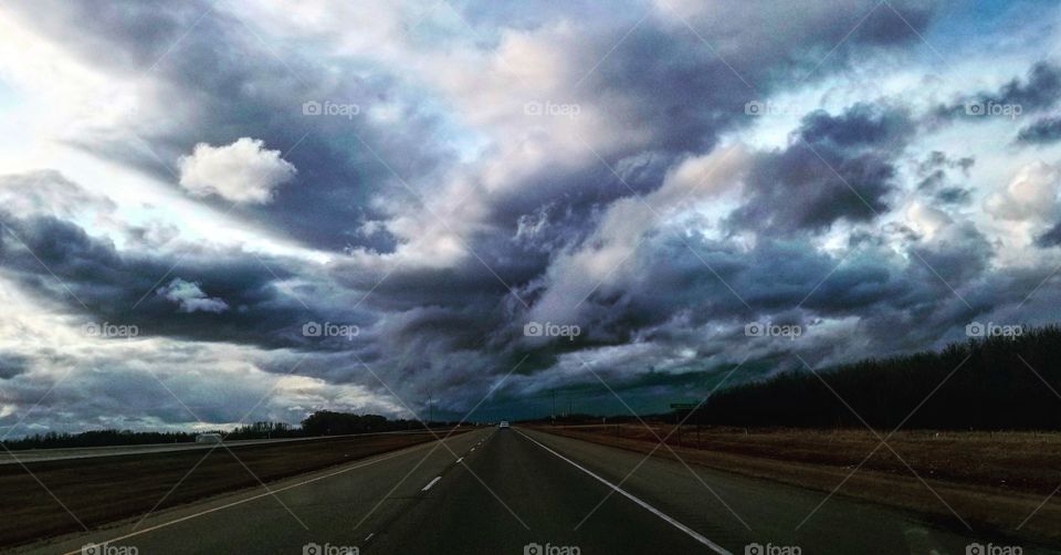 blue and purple storm clouds snd asphalt highway
