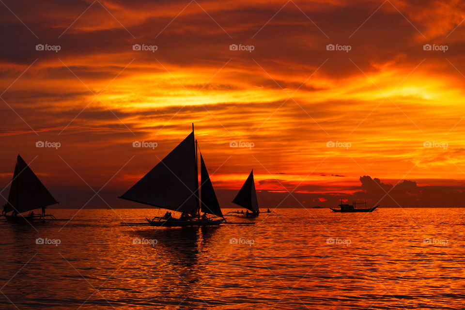Beautiful orange sunset on the sea and silhouette of sailing boats 