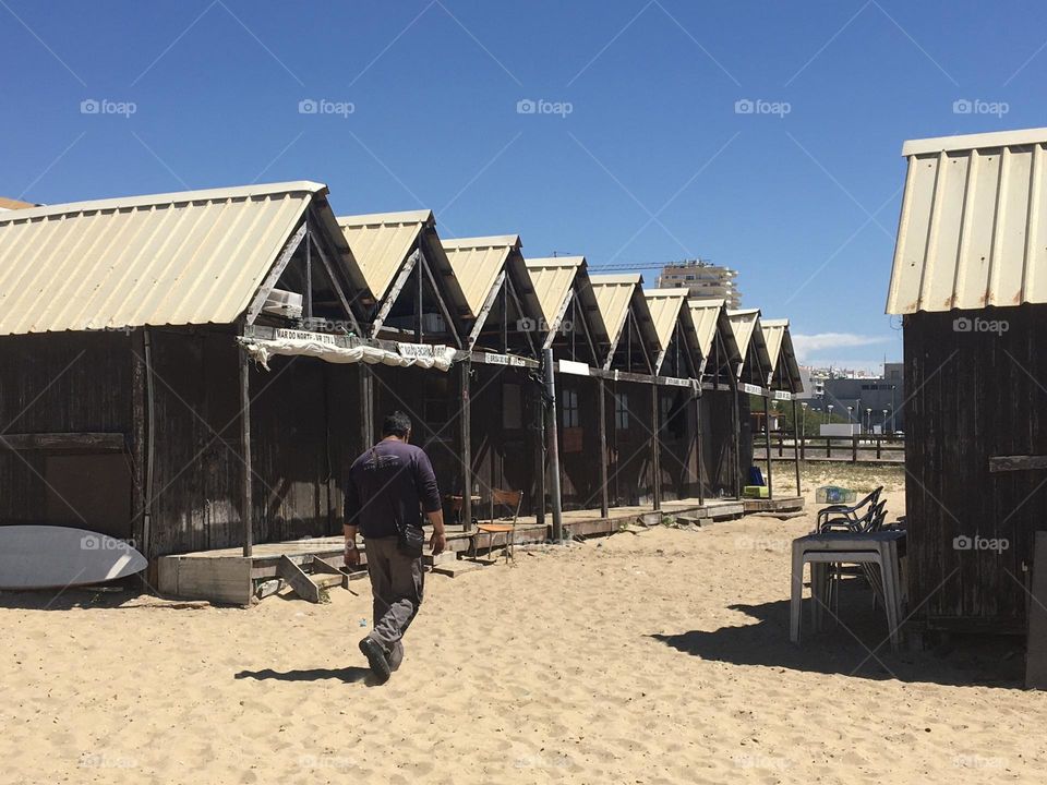 Fisherman and line of cabins on beach