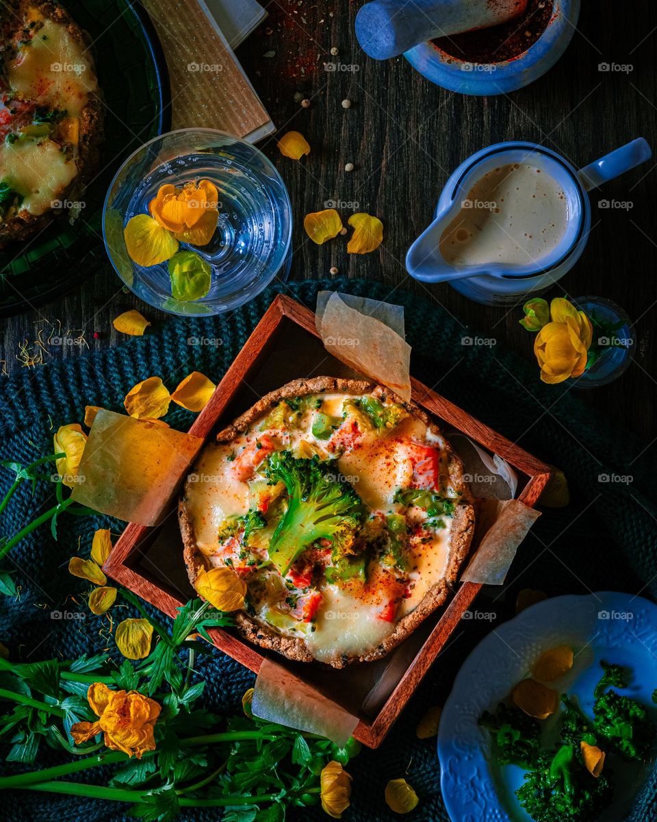 Baked homemade quiche pie in mini metal forms served with fresh greens, kitchen towel and fork in dark wood tray on old plank wooden background. Flat lay with space. High quality photo