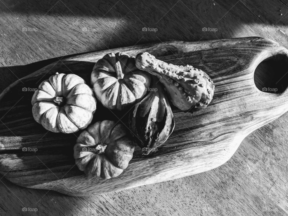 group of pumpkins on wooden cutting board black and white