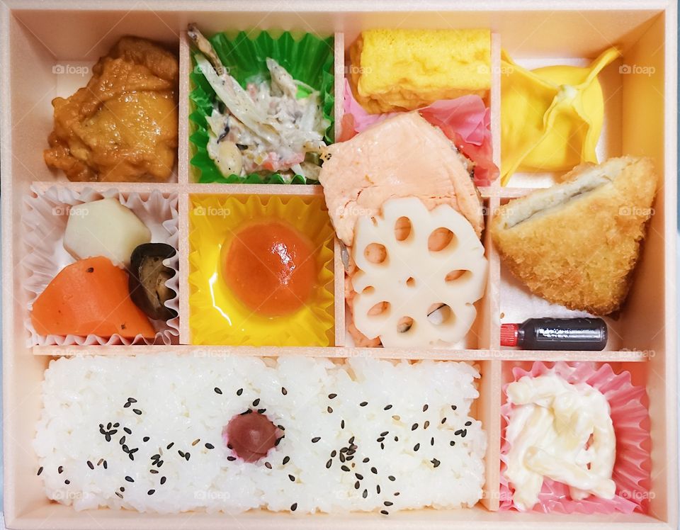 Bento box. Bento is Japanese traditional takeaway lunch box divided into small section with various food and Japanese sweet i.e. salmon fish, fried chicken, potato korokke, salad & cooked vegetables