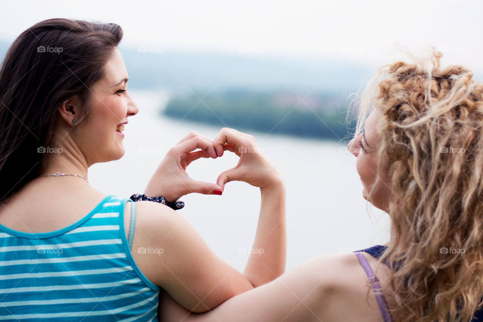 friends making heart shape. two best girl friends making heart shape of hands