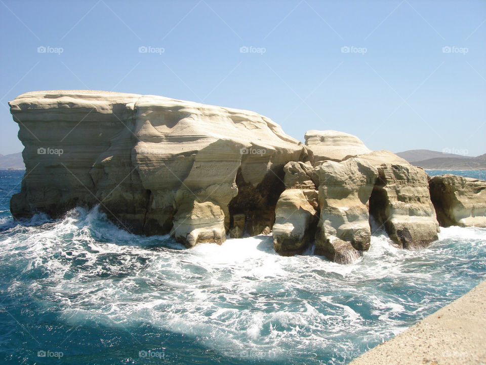 Water splashing on rocky cliff in sea