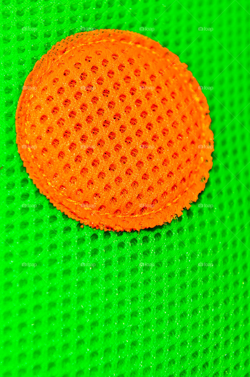 Bright orange spot sewn onto green textured fabric