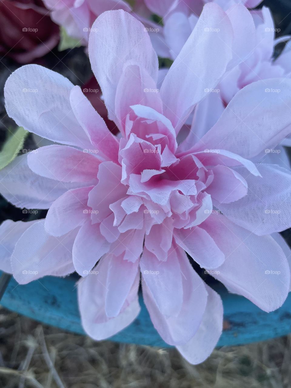A fake colorful pink flower in a blue flower pot. 