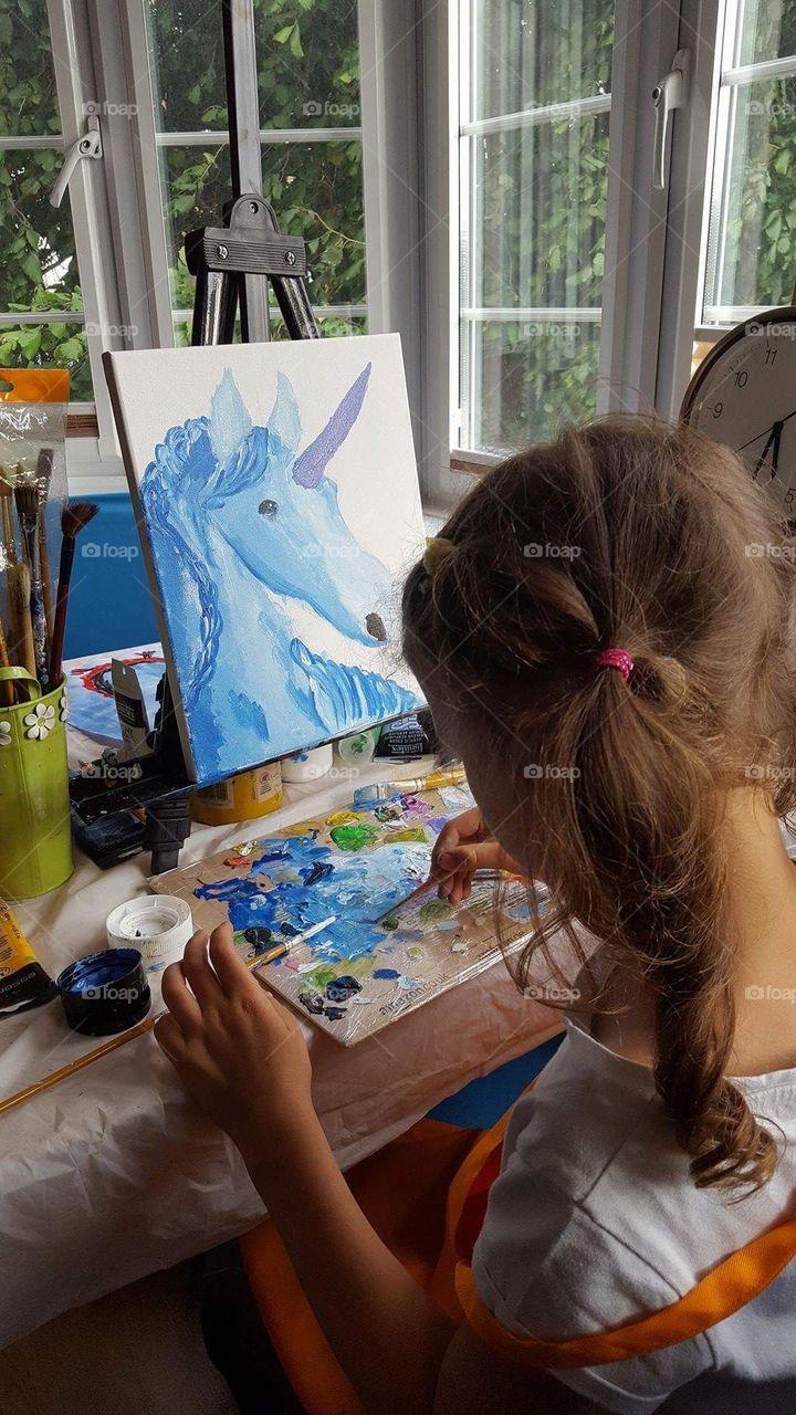 Beautiful painting. Little girl drawing a unicorn.