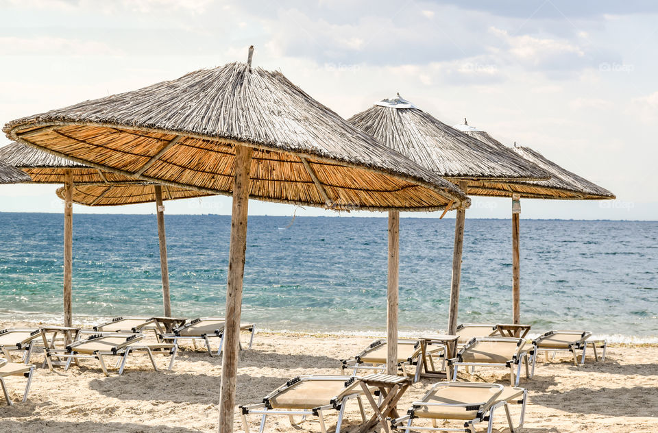 Straw Beach Umbrellas And Sunbeds On The Beach
