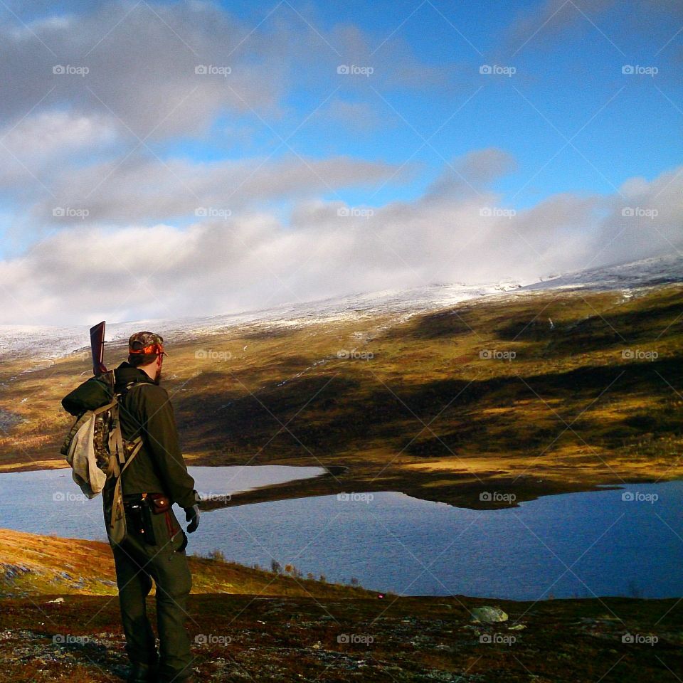 Hunter standing on mountain with gun