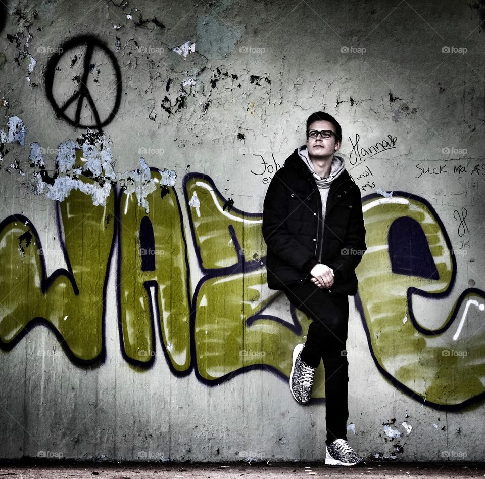 Young man posing against graffiti wall