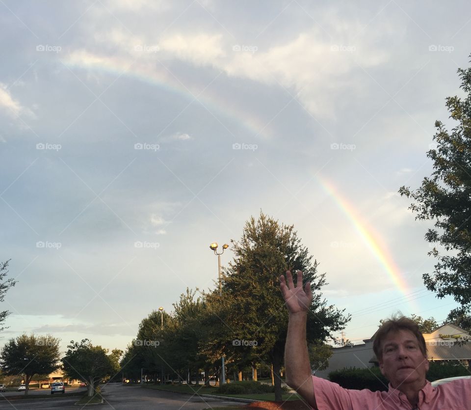 Rainbow over a shopping center with a man photo bombing my photo