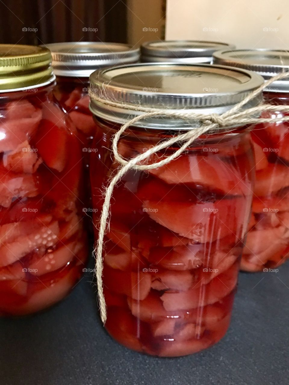 Canning or “putting up” quince fruit preserves in quart glass jars