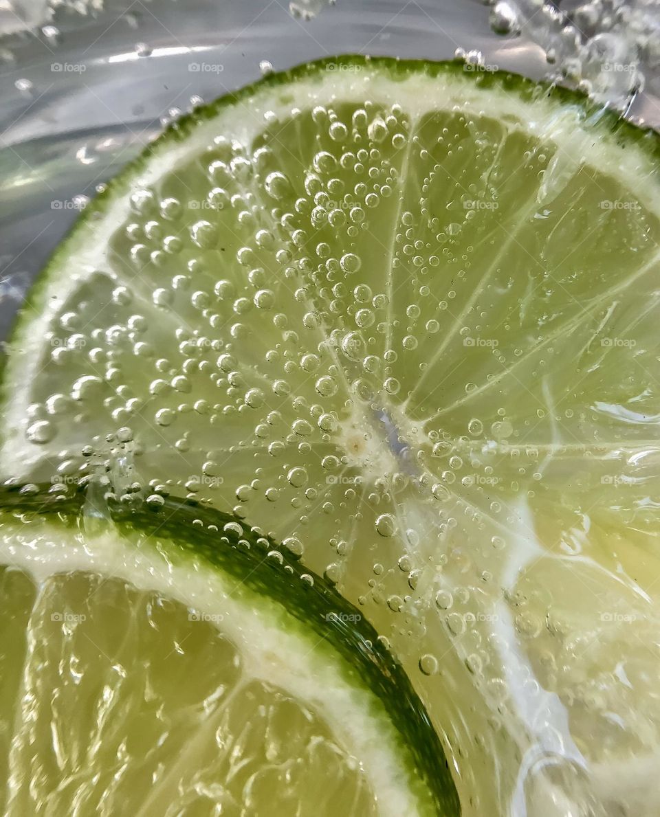 Mineral water fizzing against slices of lime 