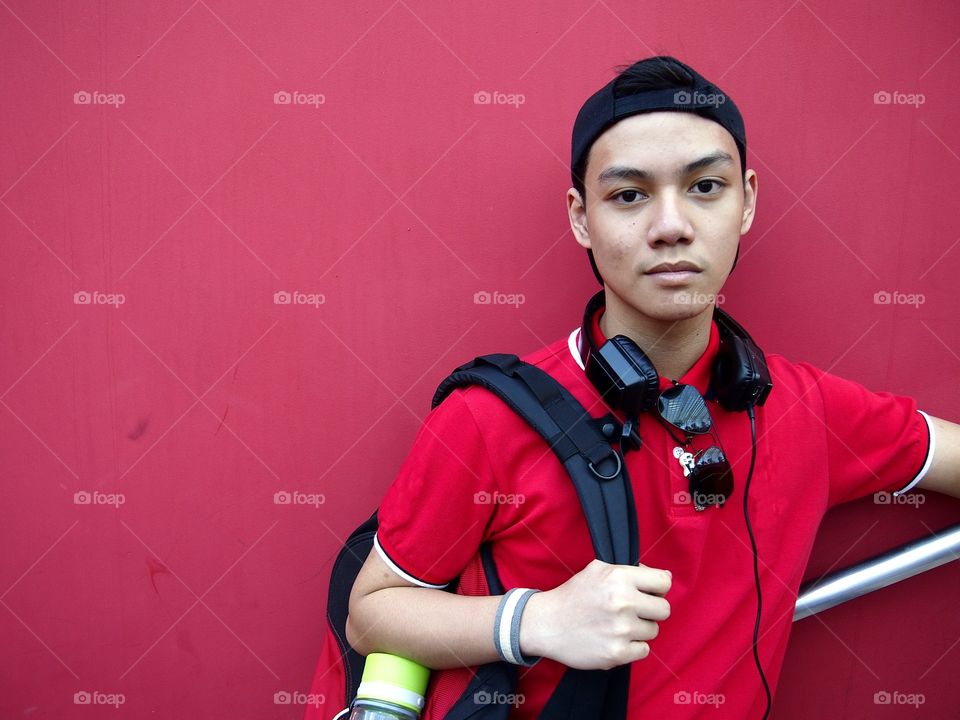 young teenage boy with backpack, sunglasses, cap and ear phones