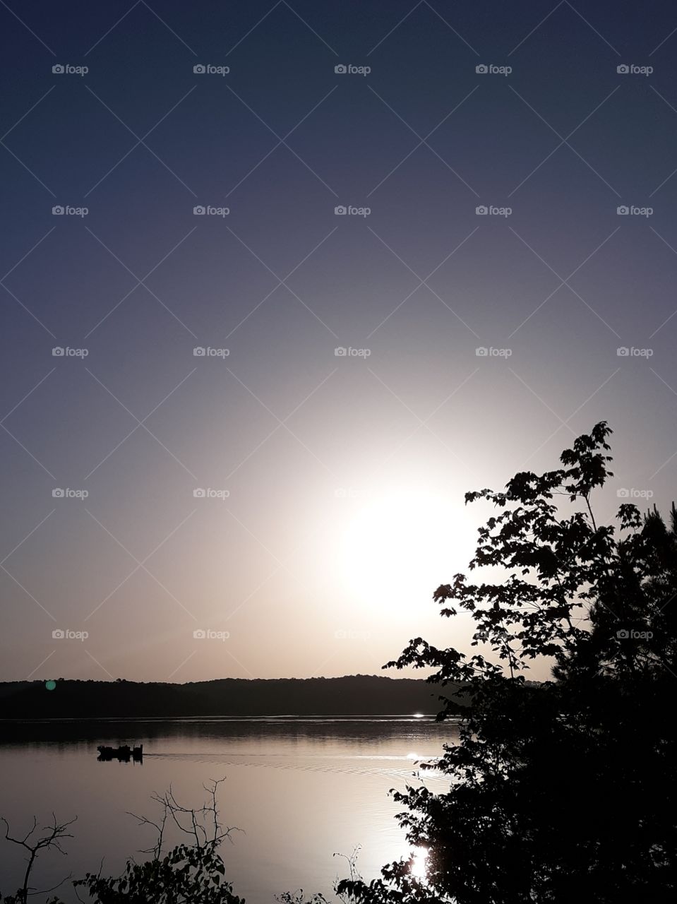 Boat gliding across still water with the sun rising