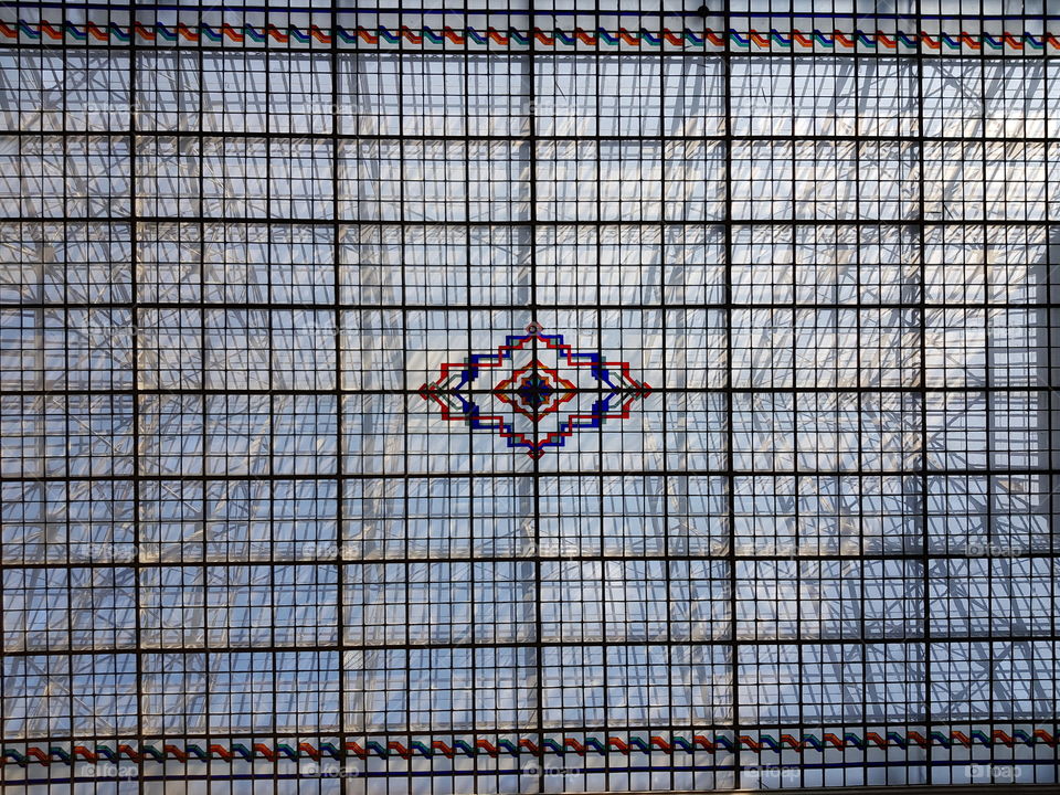 Giant glass roof with rectangular structure and colored pattern in the centre.