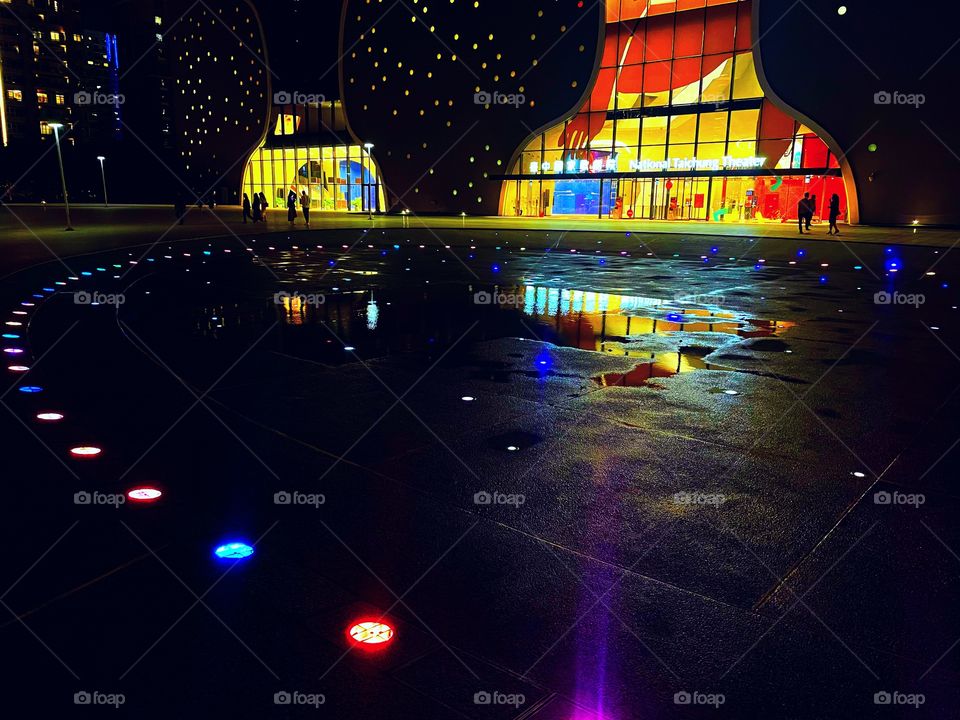 A giant puddle on the ground. Several lights of various colours come out from under the ground. 