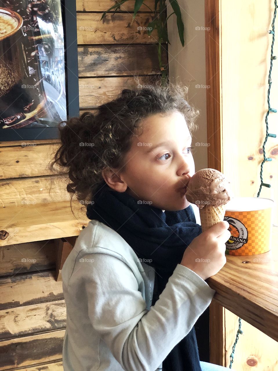 Child eating ice cream cone in window seat 