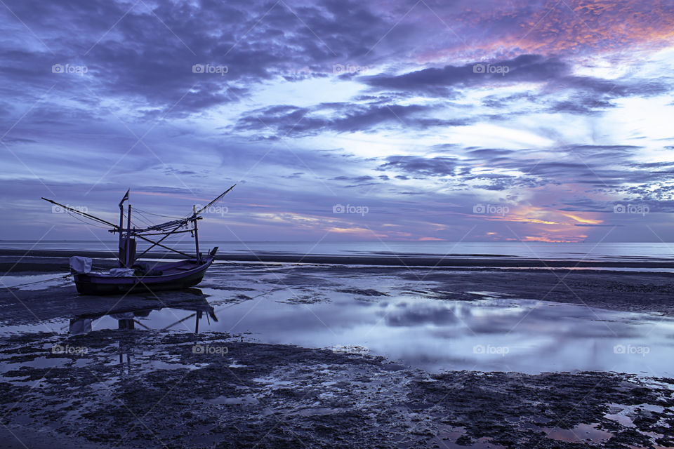 The morning sun light in the sea and the boat on the beach.