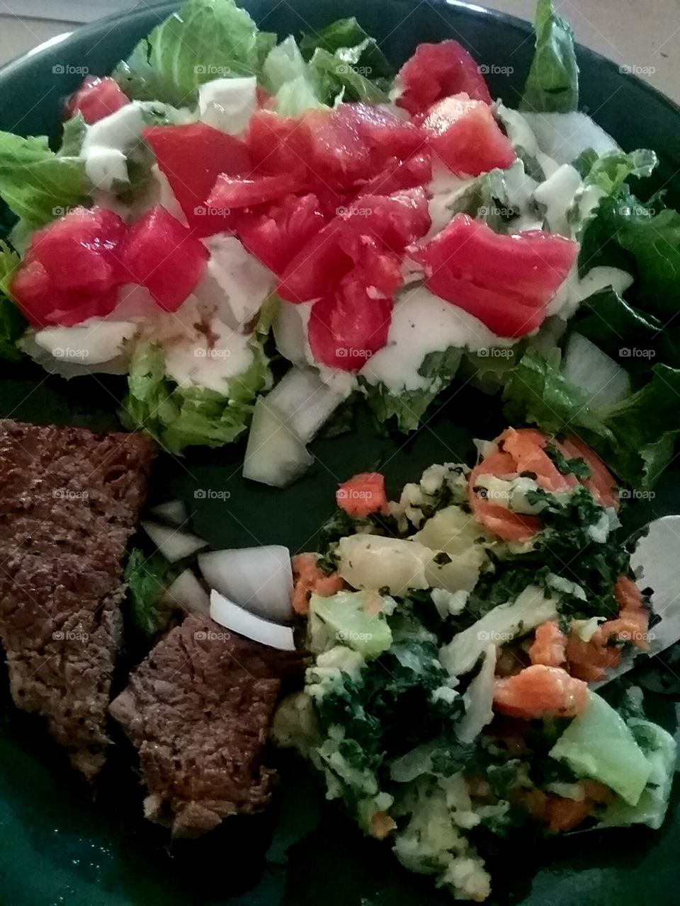 steak and salad.with organic  romaine lettuce fresh tomatoes onion and more cooked veggies on the side