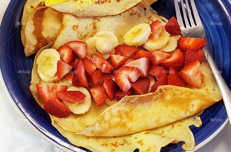 delicious sliced strawberry and banana fruit and scrambled egg crepes plate breakfast