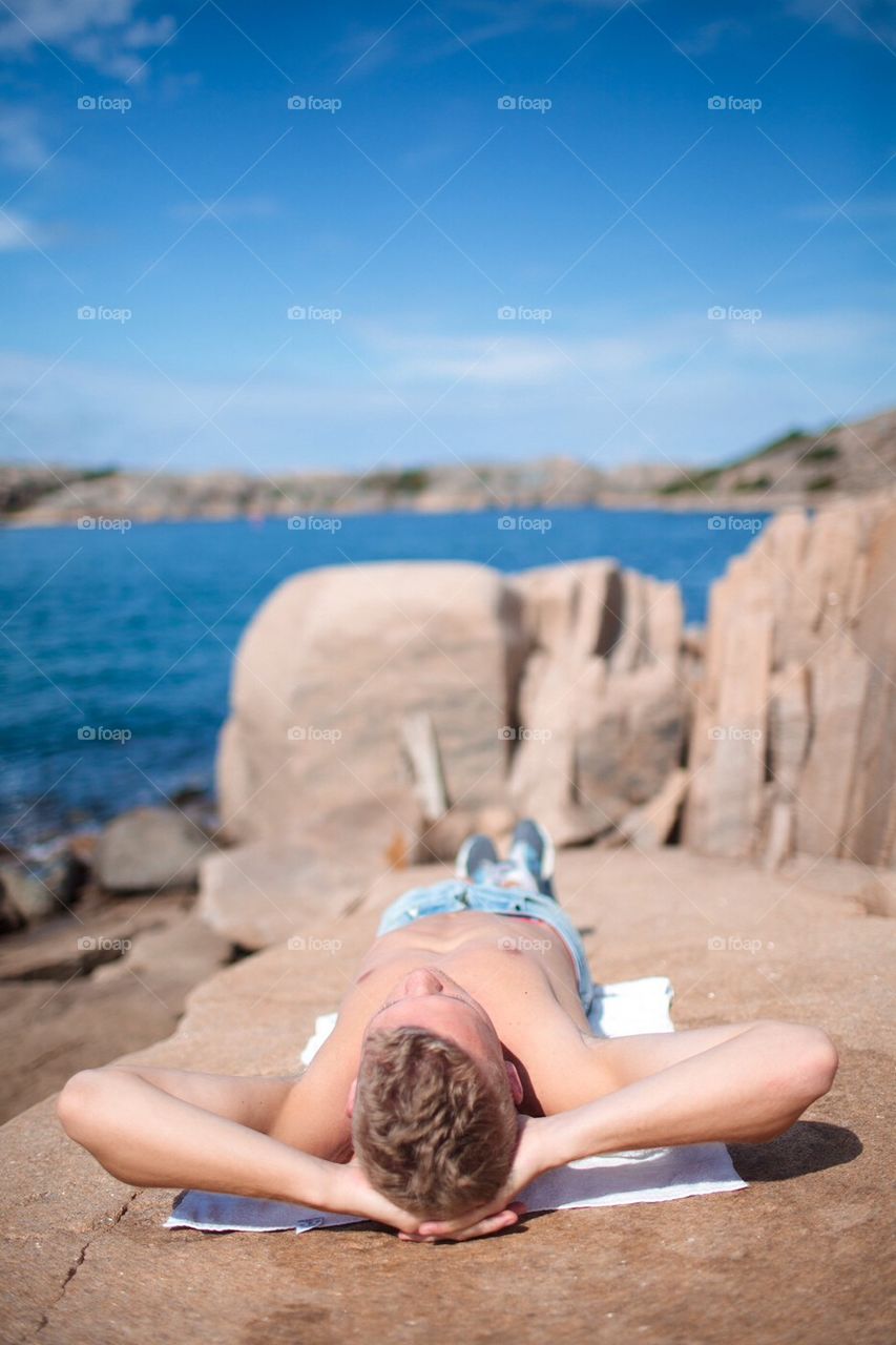 Man sunbathing on a seaside cliff