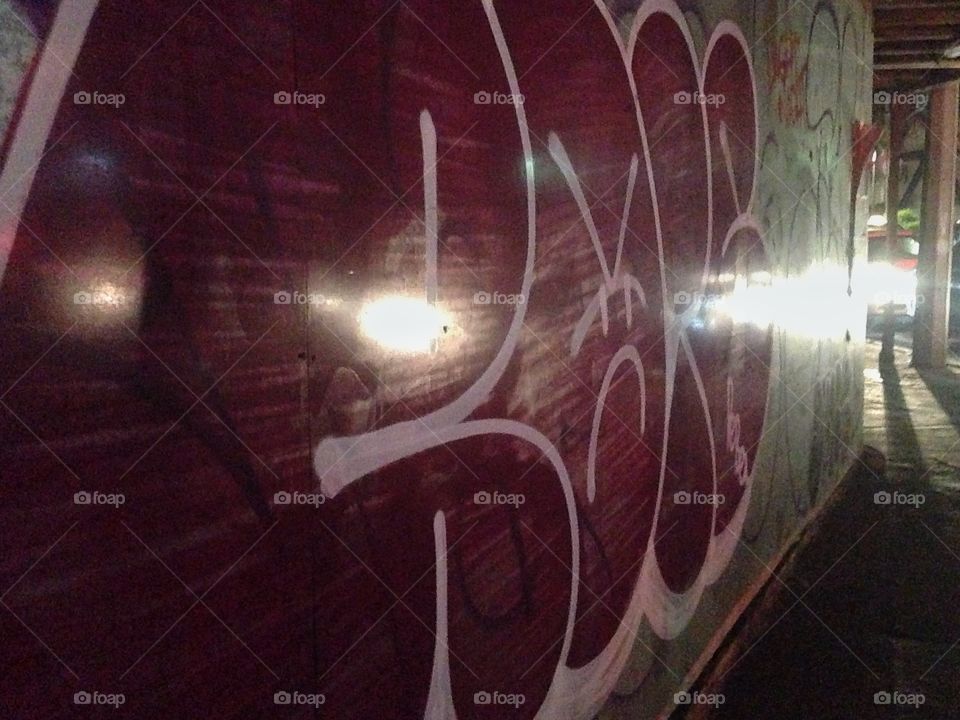 A re graffiti iluminated by the lights of the cars.