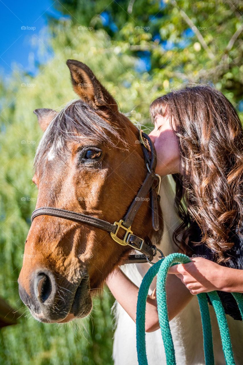 Beautiful brunette woman kissing her horse