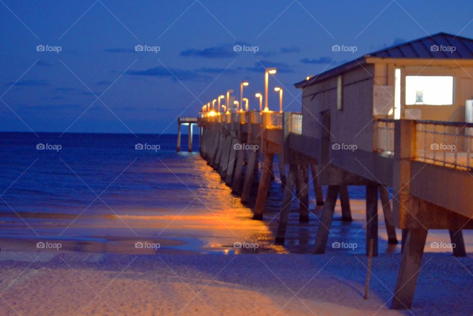 Illuminated pier on beach at night