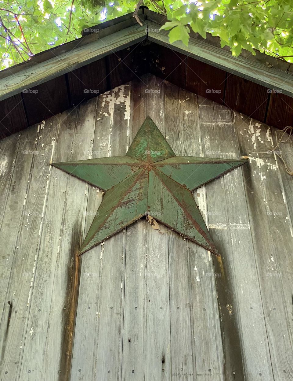 A painted metal barn star on an old weathered wooden barn