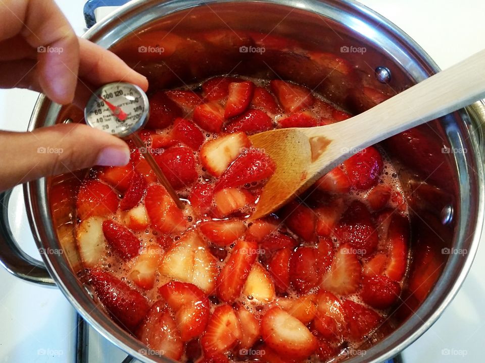 Checking temperature of sugar strawberry mixture while making jam