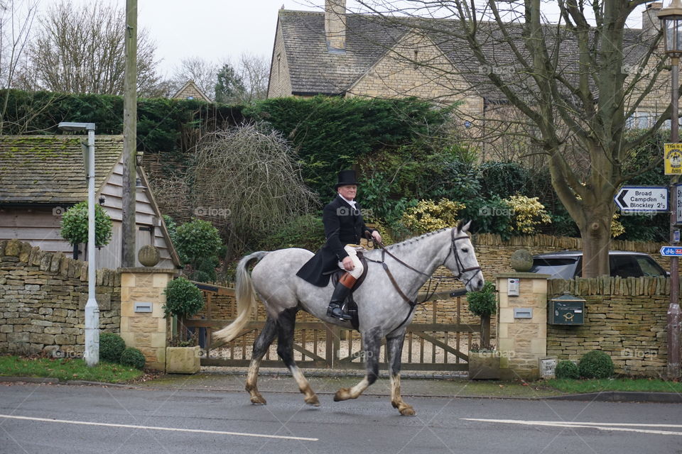 Man riding his horse through a Cotswold Village ...