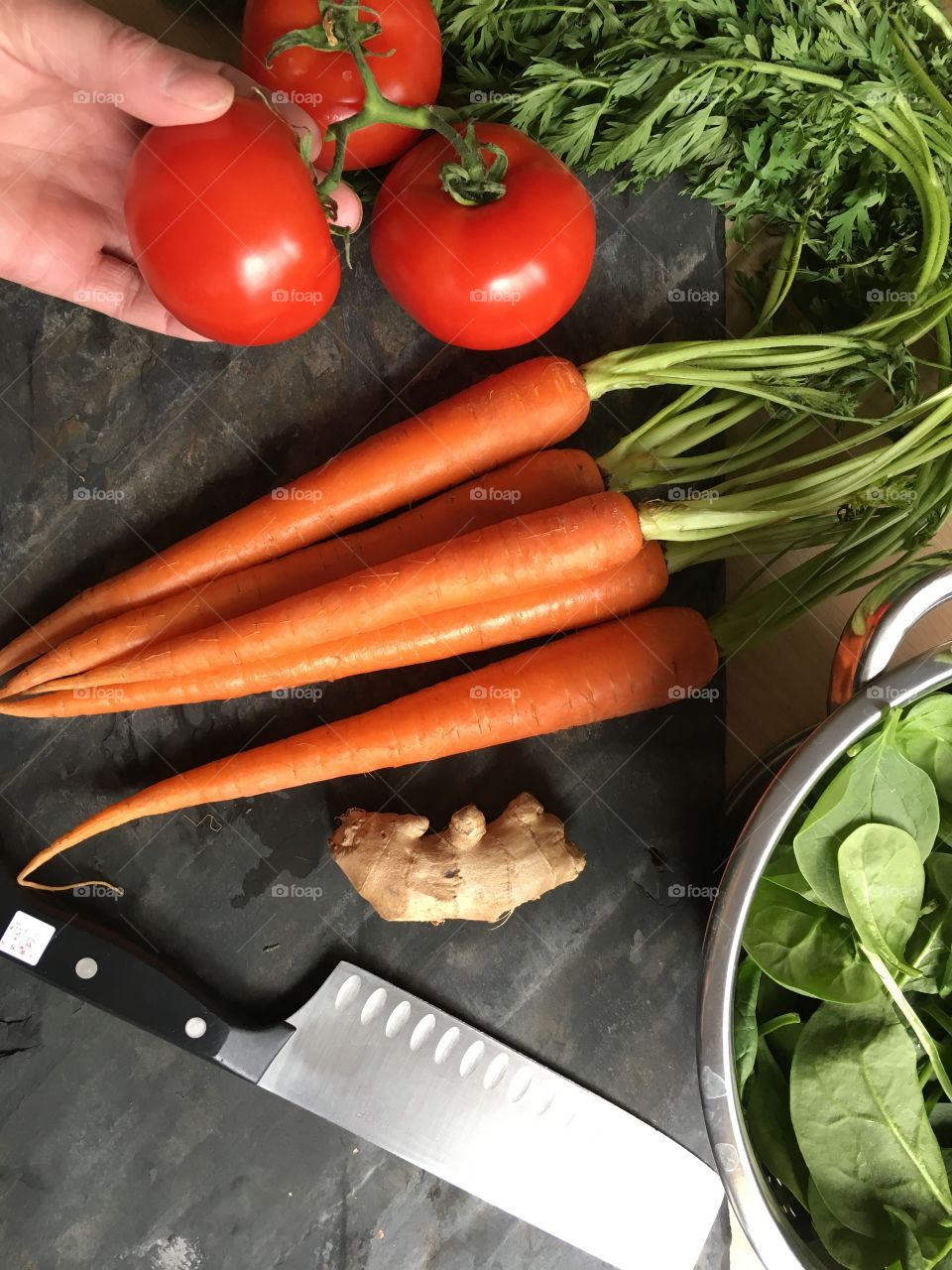 Cooking with fresh vegetables; tomatoes, baby spinach, organic carrots, ginger root. Healthy spring time meals.