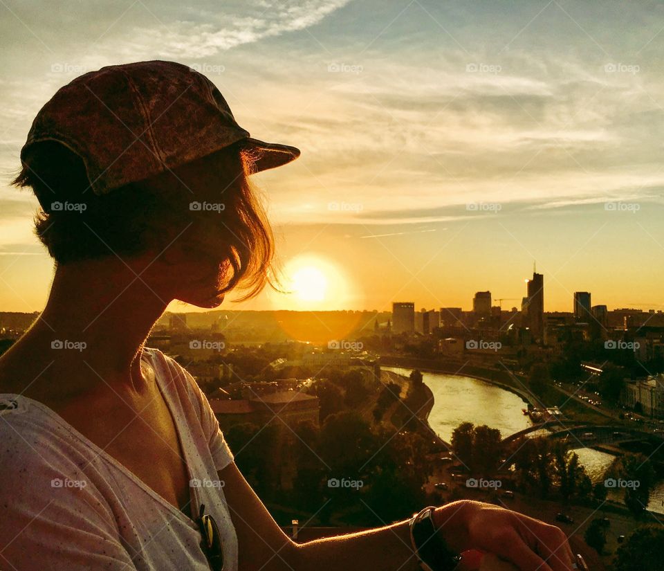 Silhouette of girl watching sunset over Vilnius. 