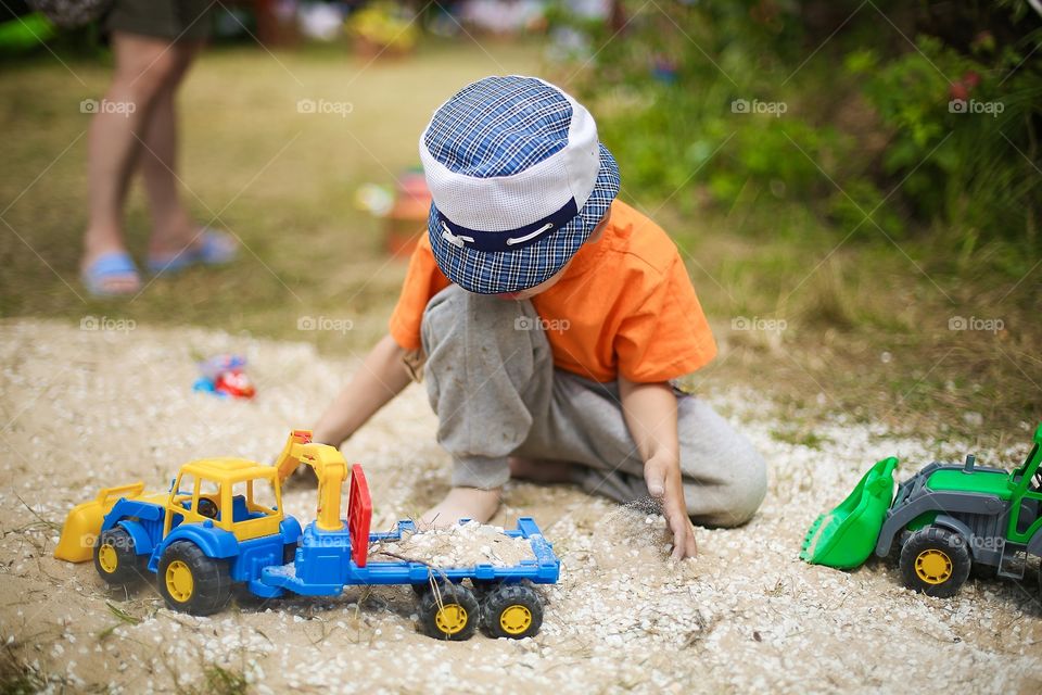 Boy playing outdoor. Sandbox with a toys
