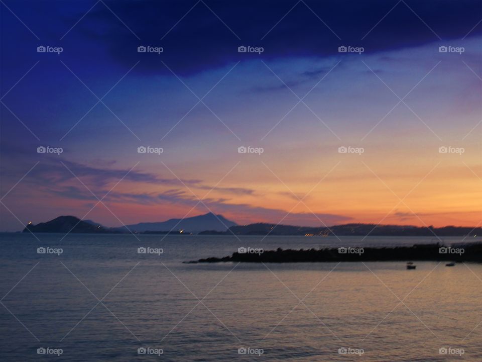 Scenic view of mountain near sea at dusk