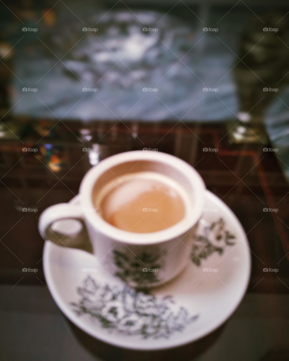 Abstract background of cup of coffee on glass table in blurred style, blurred background.