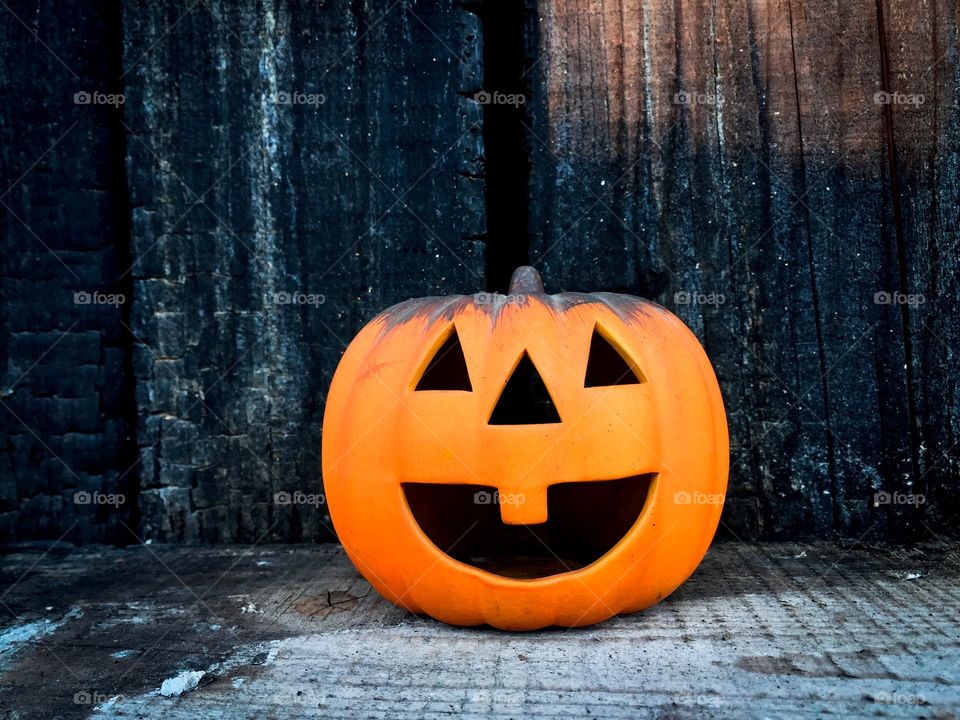 Smiling carved pumpkin surrounded by rustic wooden background 