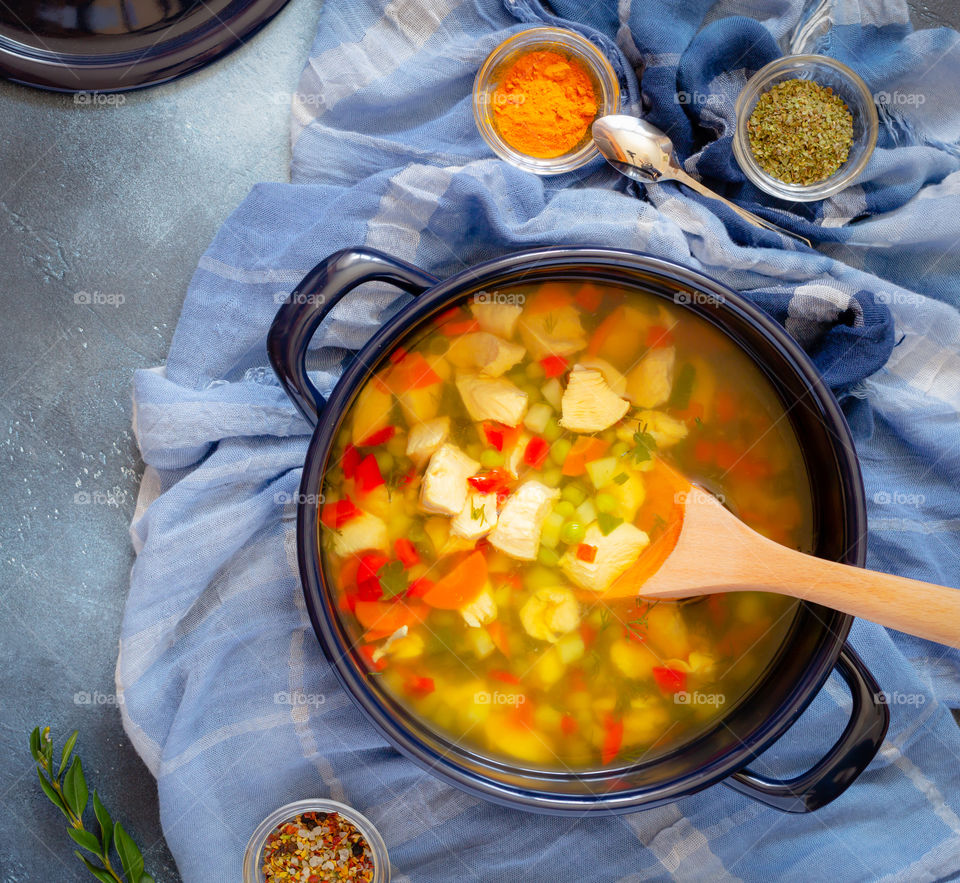 Cooking meat soup. A large blue pot with homemade chicken soup with turmeric and spices in bowls on a blue background. The concept of simple healthy food. Food photos, top view