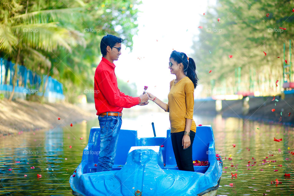 Young Asian couple proposing on boat with rose flower