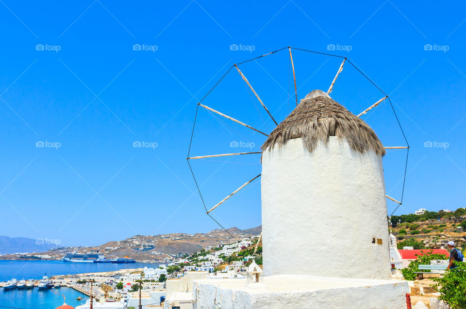 Windmill on island Mykonos . Traditional windmill on island Mykonos with the city view, Mediterranean sea, Greece 