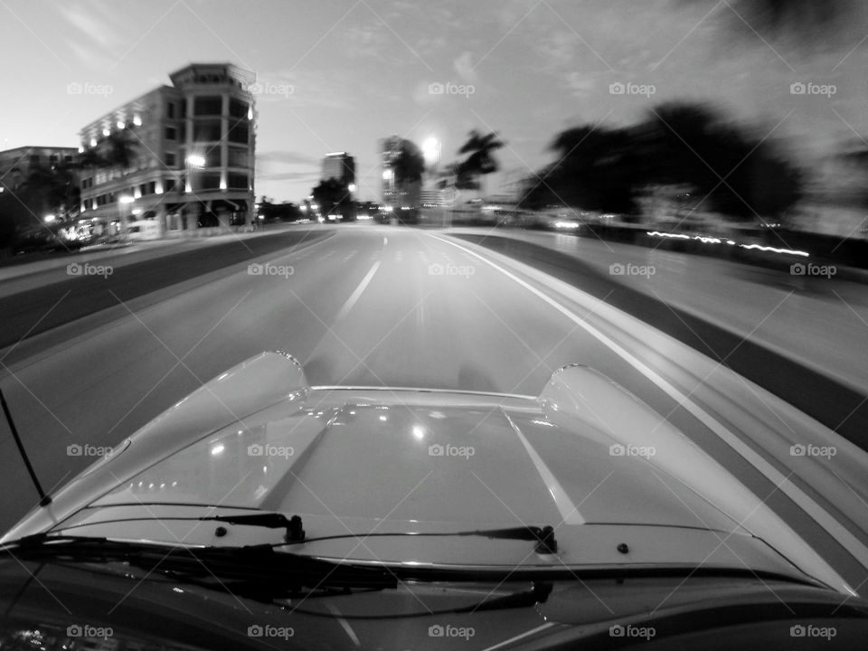 Night Drive. A classic car drives down a waterfront street on a clear evening. 